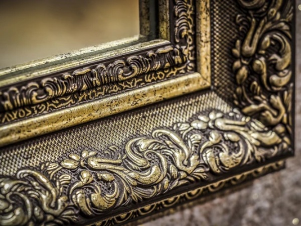 A close up of the ornate frame on a mirror