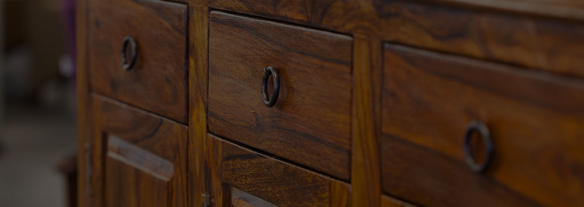 A close up of the drawer and handle on a wooden dresser.